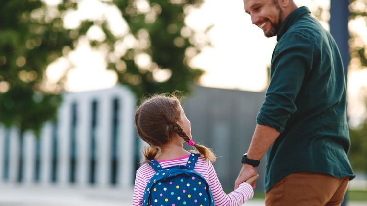 Dad and child with backpack hand in hand on campus, dad takes child to daycare